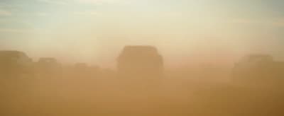 a group of trucks driving through a foggy field