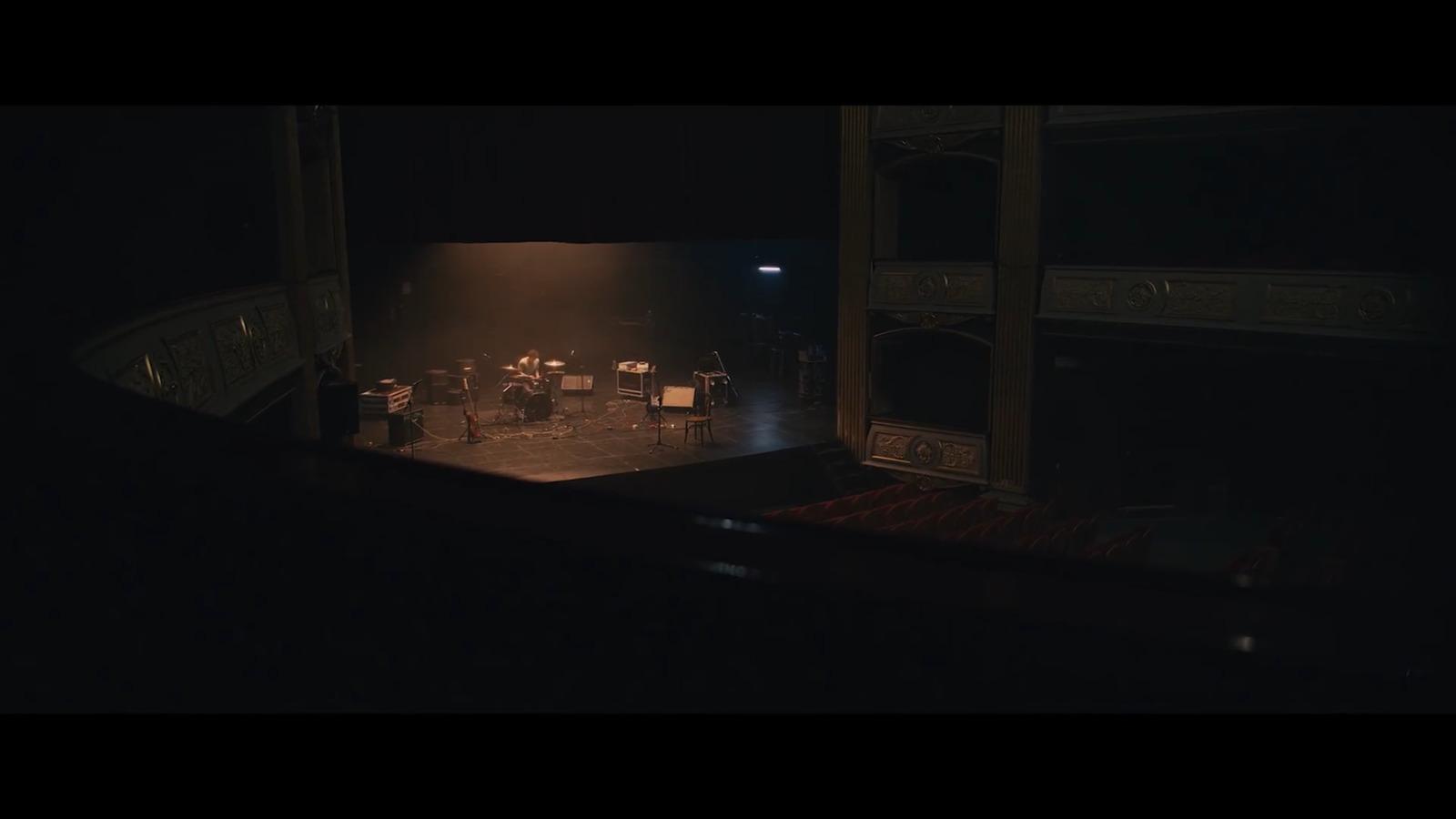 a dark stage with chairs and a piano