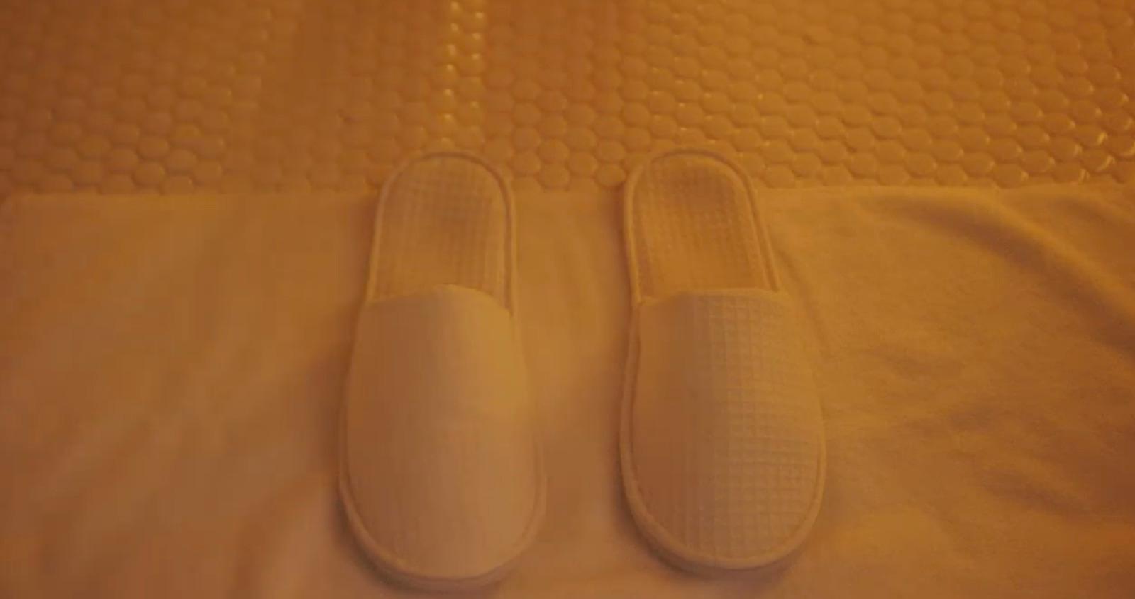 a pair of white slippers sitting on top of a bed