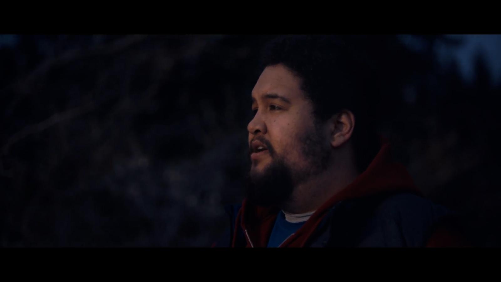 a man with a beard standing in the dark