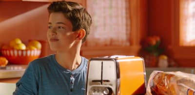 a young boy holding a toaster in a kitchen