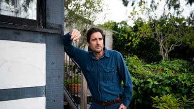 a man leaning against a wall in front of a house