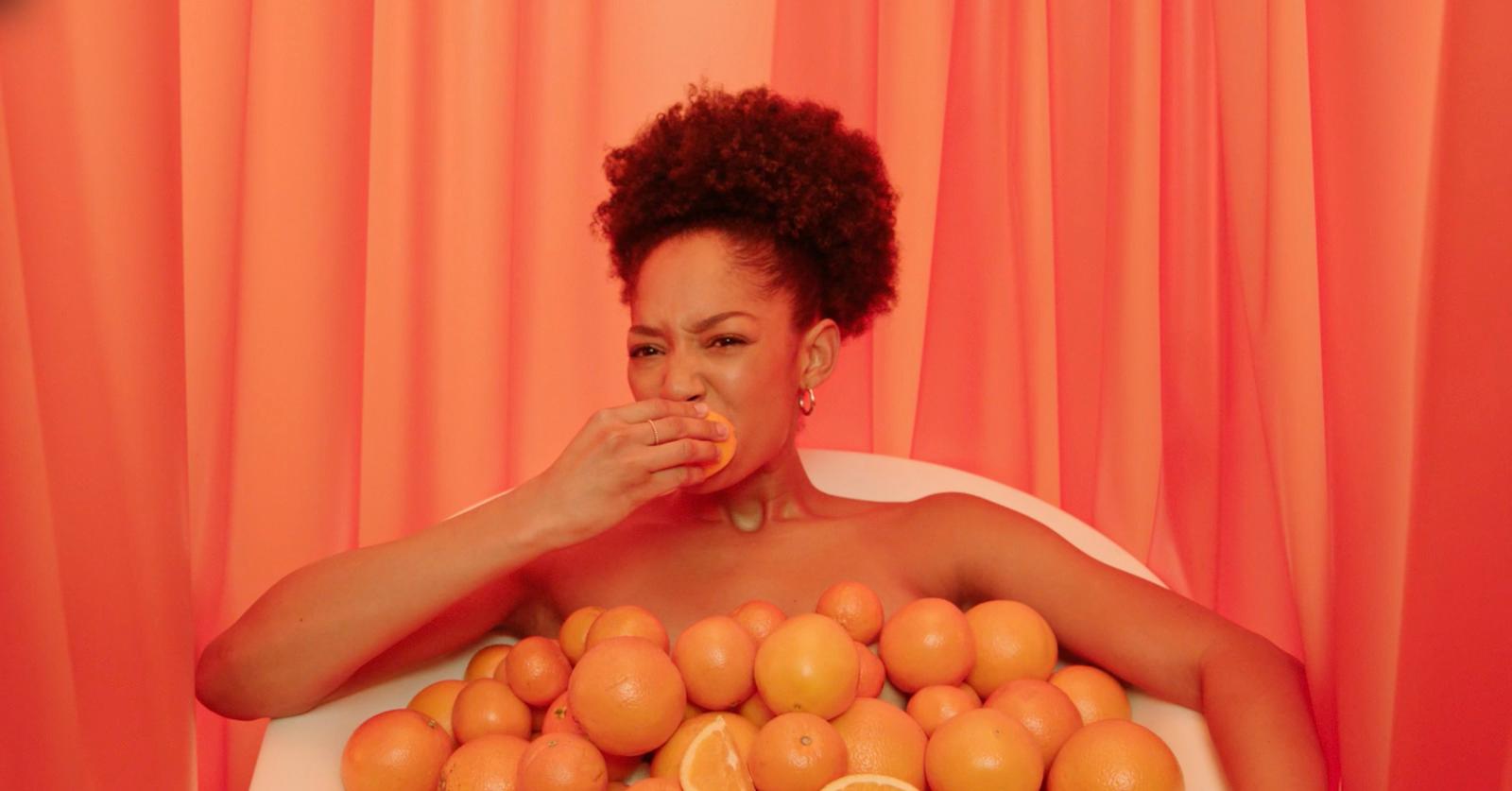 a woman sitting in a bathtub covered in oranges