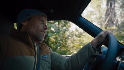 a man driving a car through a forest
