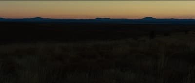 the sun is setting over the mountains in the distance