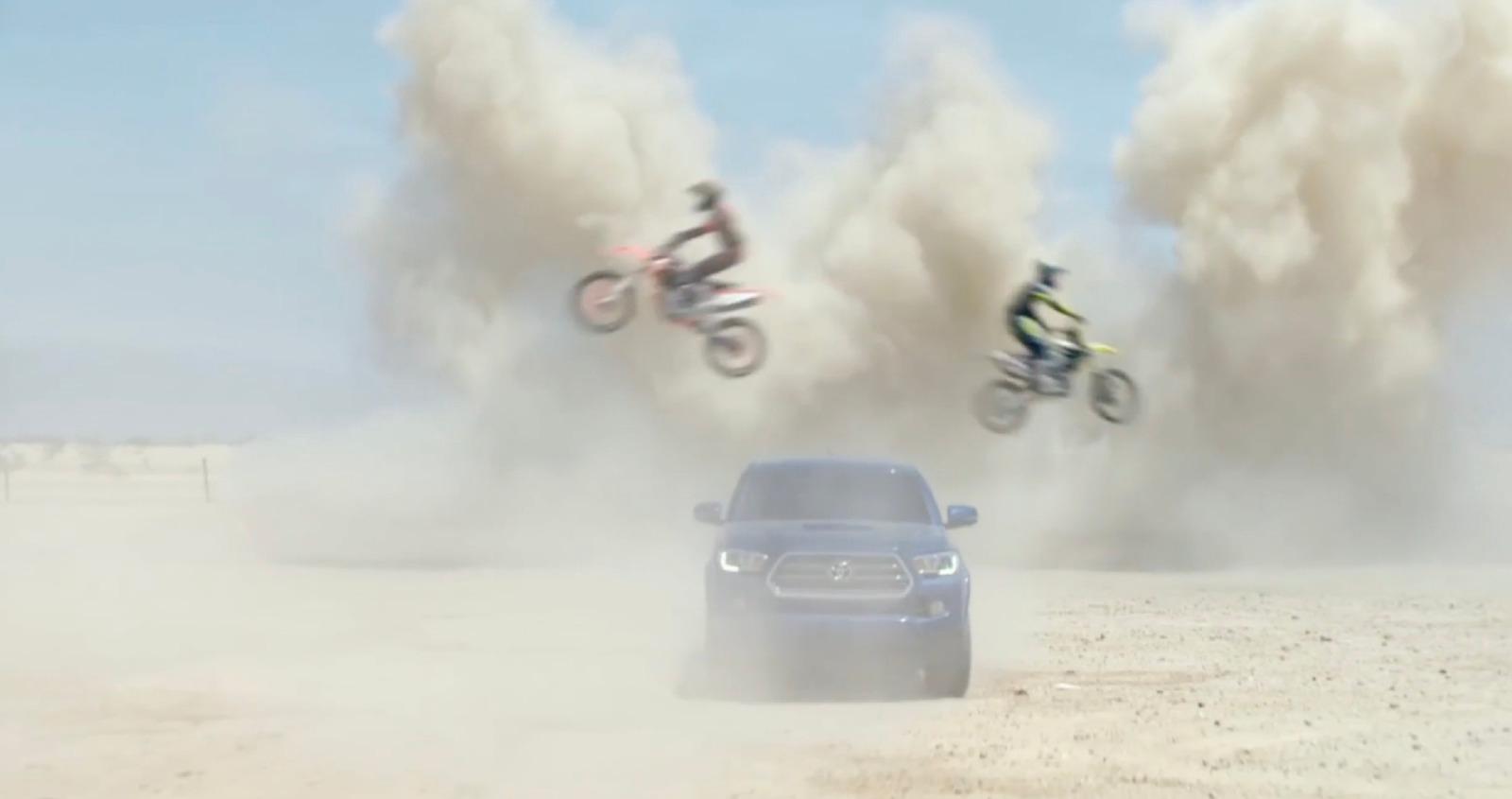 a car driving down a dirt road next to a motorcycle