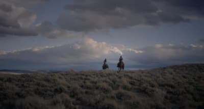 two people riding horses on a cloudy day