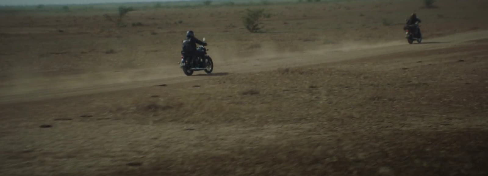 two people riding motorcycles on a dirt road