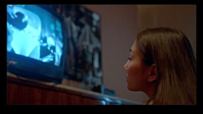a young girl watching a movie on tv