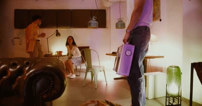a man standing in a living room holding a purple bag