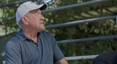 an older man wearing a baseball cap sitting next to a younger man