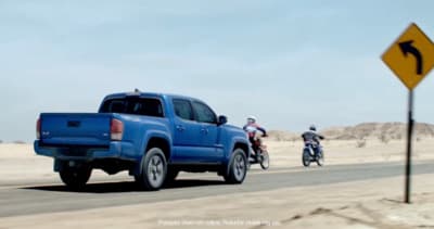 a blue pick up truck driving down a desert road
