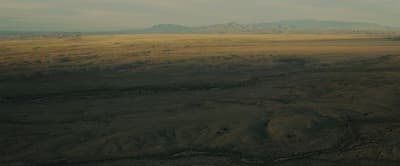 an aerial view of a plain with mountains in the distance