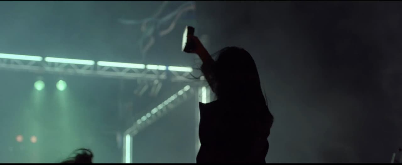 a woman standing in front of a stage holding a cell phone