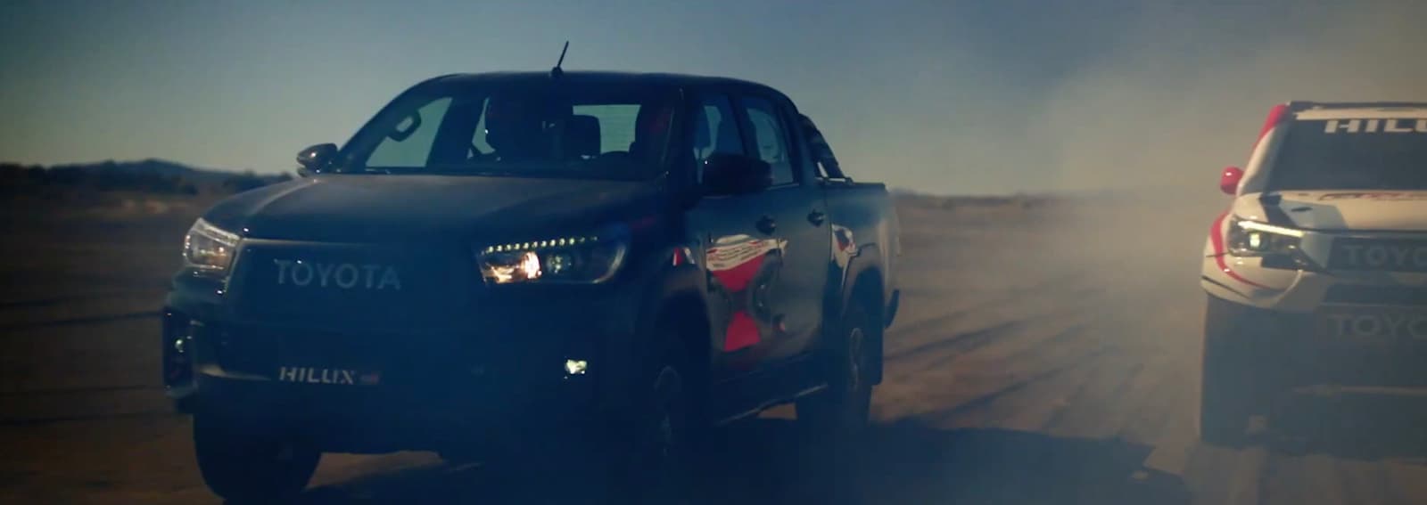 a couple of cars driving down a dirt road