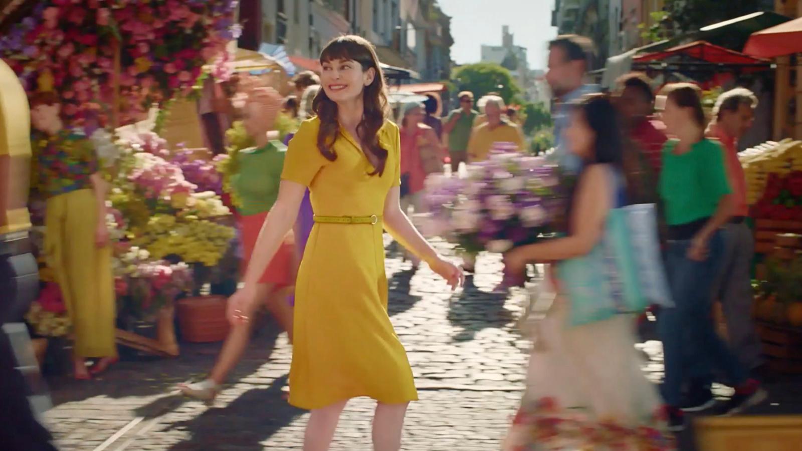 a woman in a yellow dress walking down a street