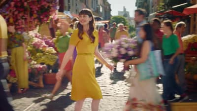 a woman in a yellow dress walking down a street