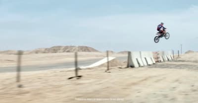 a person on a dirt bike jumping over a fence