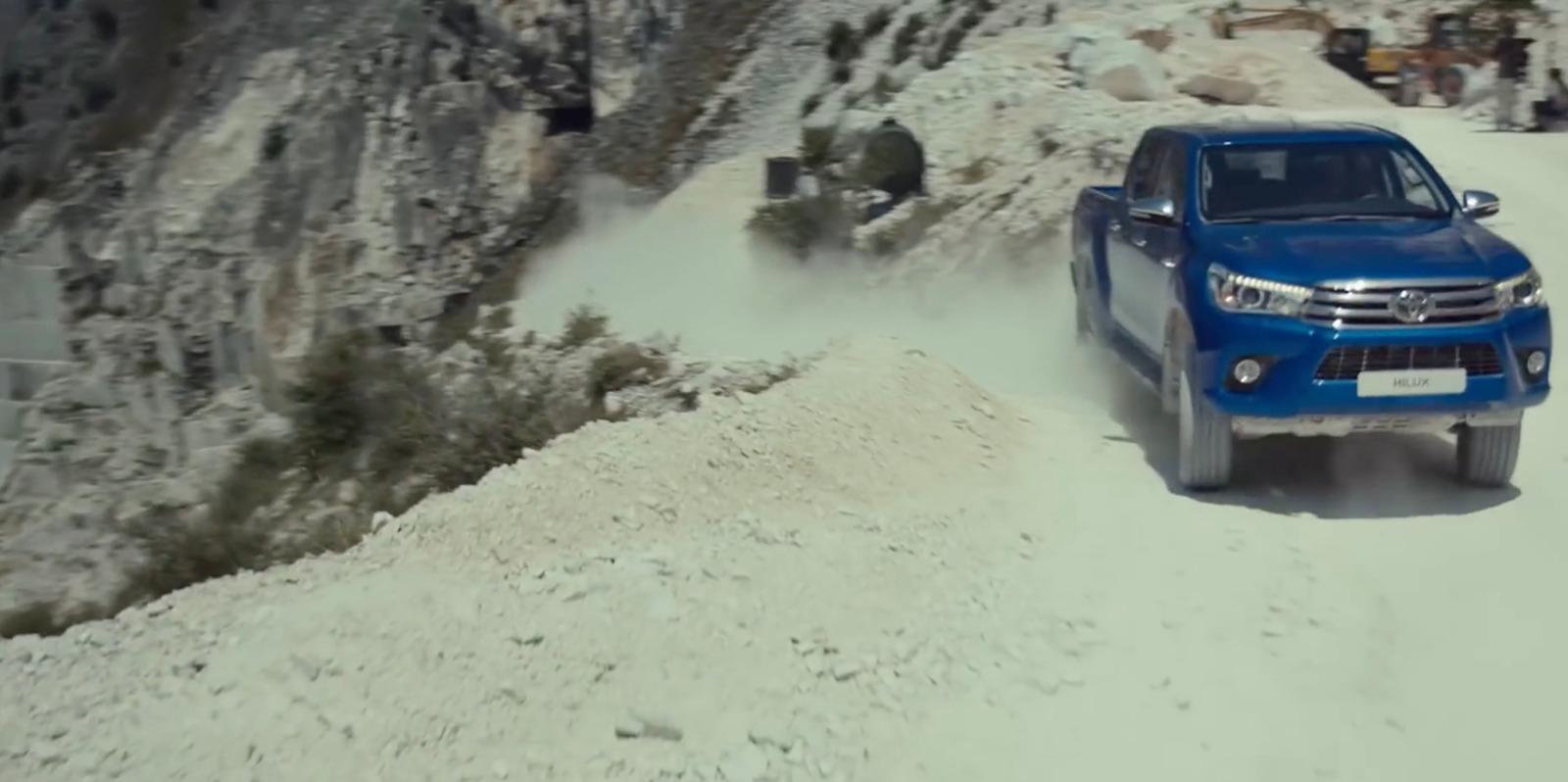 a blue truck driving down a snow covered road