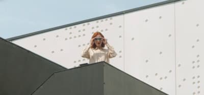 a woman wearing sunglasses standing on top of a building