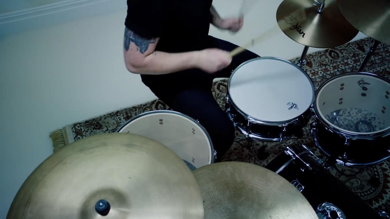 a man with a tattoo on his arm playing drums