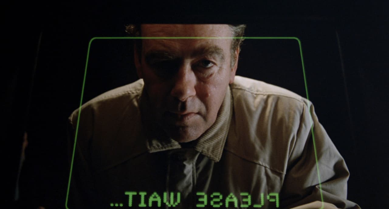 a man is looking at a screen with the words please wait
