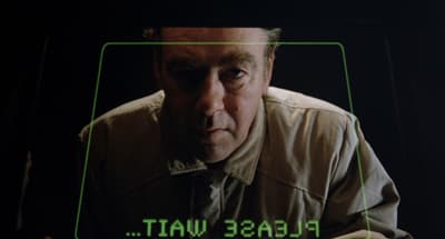 a man is looking at a screen with the words please wait