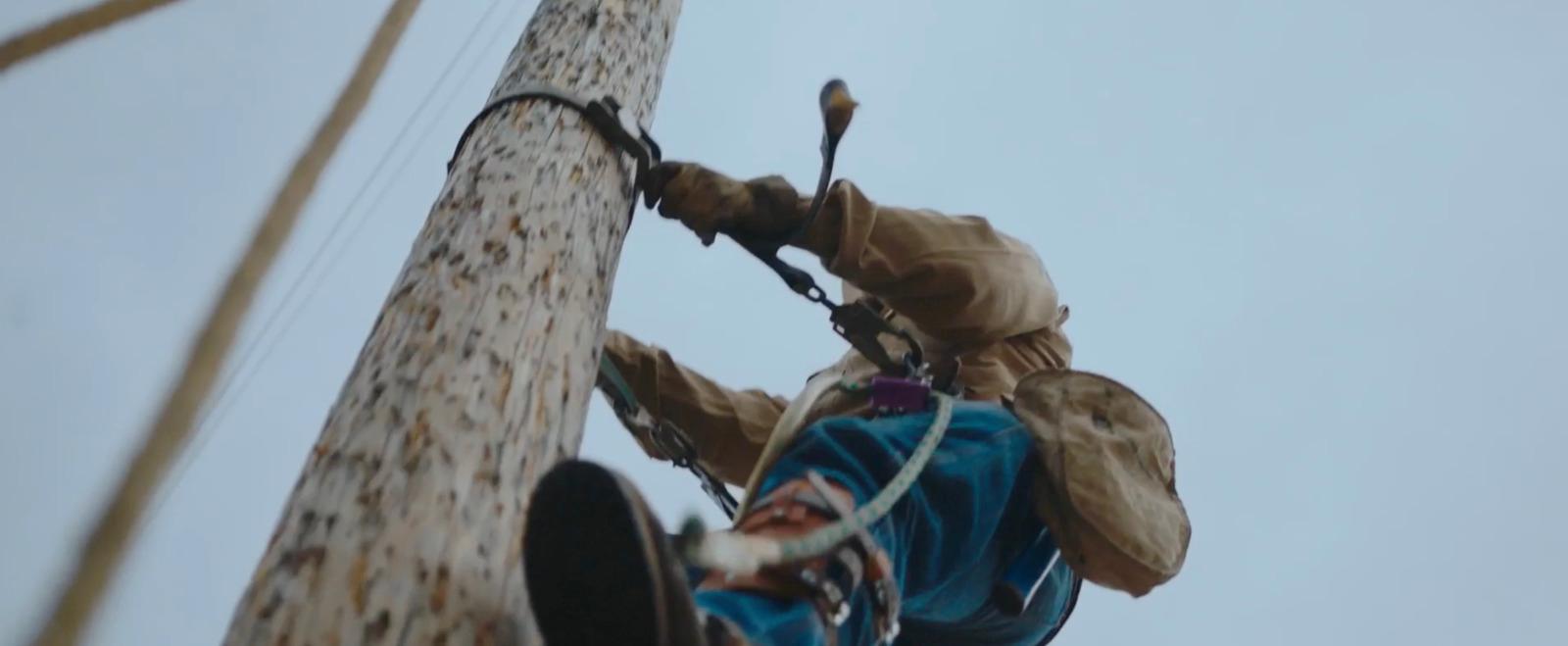 a man climbing up a tall wooden pole