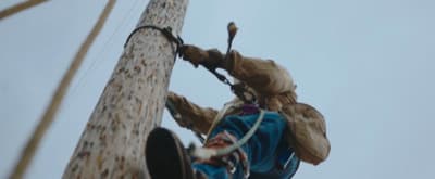 a man climbing up a tall wooden pole