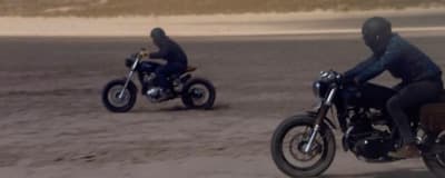 two people riding motorcycles on a sandy beach