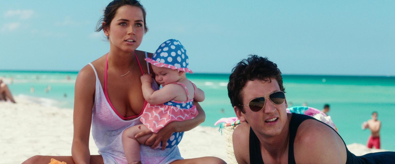 a man and a woman on the beach with a baby