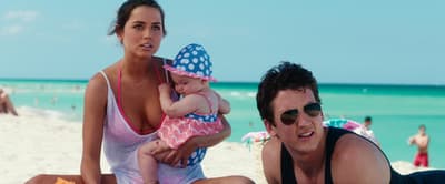 a man and a woman on the beach with a baby