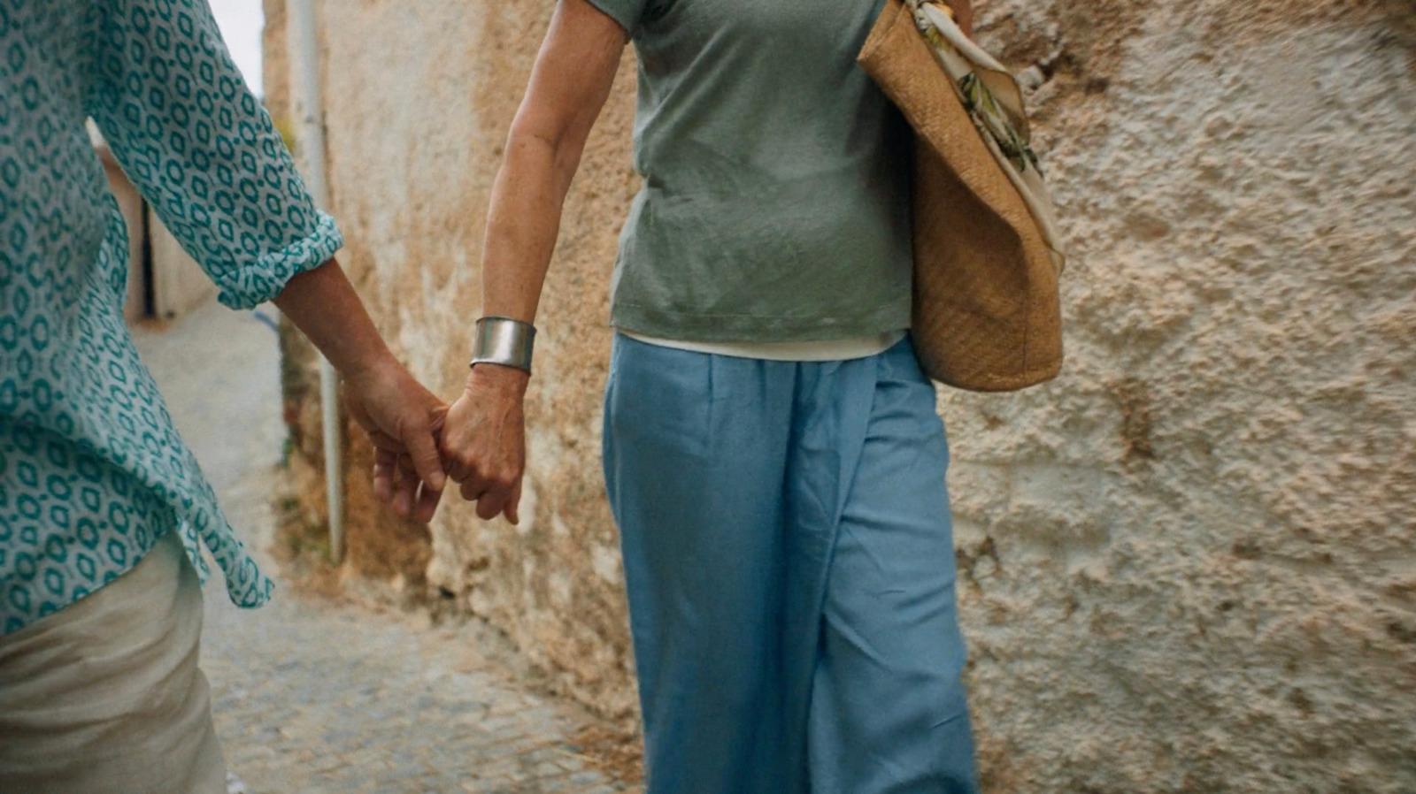 a couple of people walking down a street holding hands