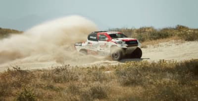 a red and white truck driving down a dirt road