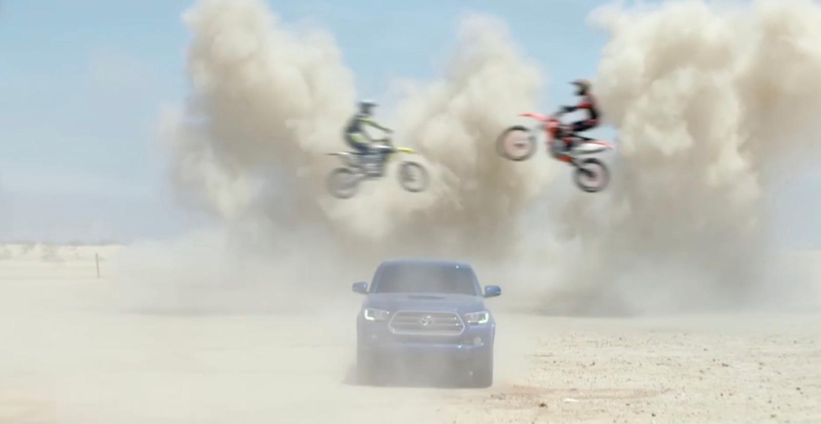 a car and two motorcyclists flying over a car in the desert