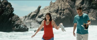 a man and a woman playing frisbee on the beach