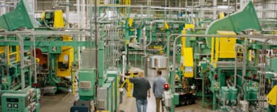 two men walking through a factory with machinery