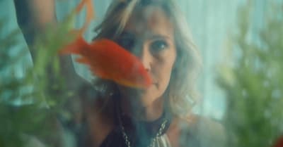 a woman looking through a window at a goldfish