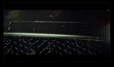 a close up of a metal fence with a rainbow in the background