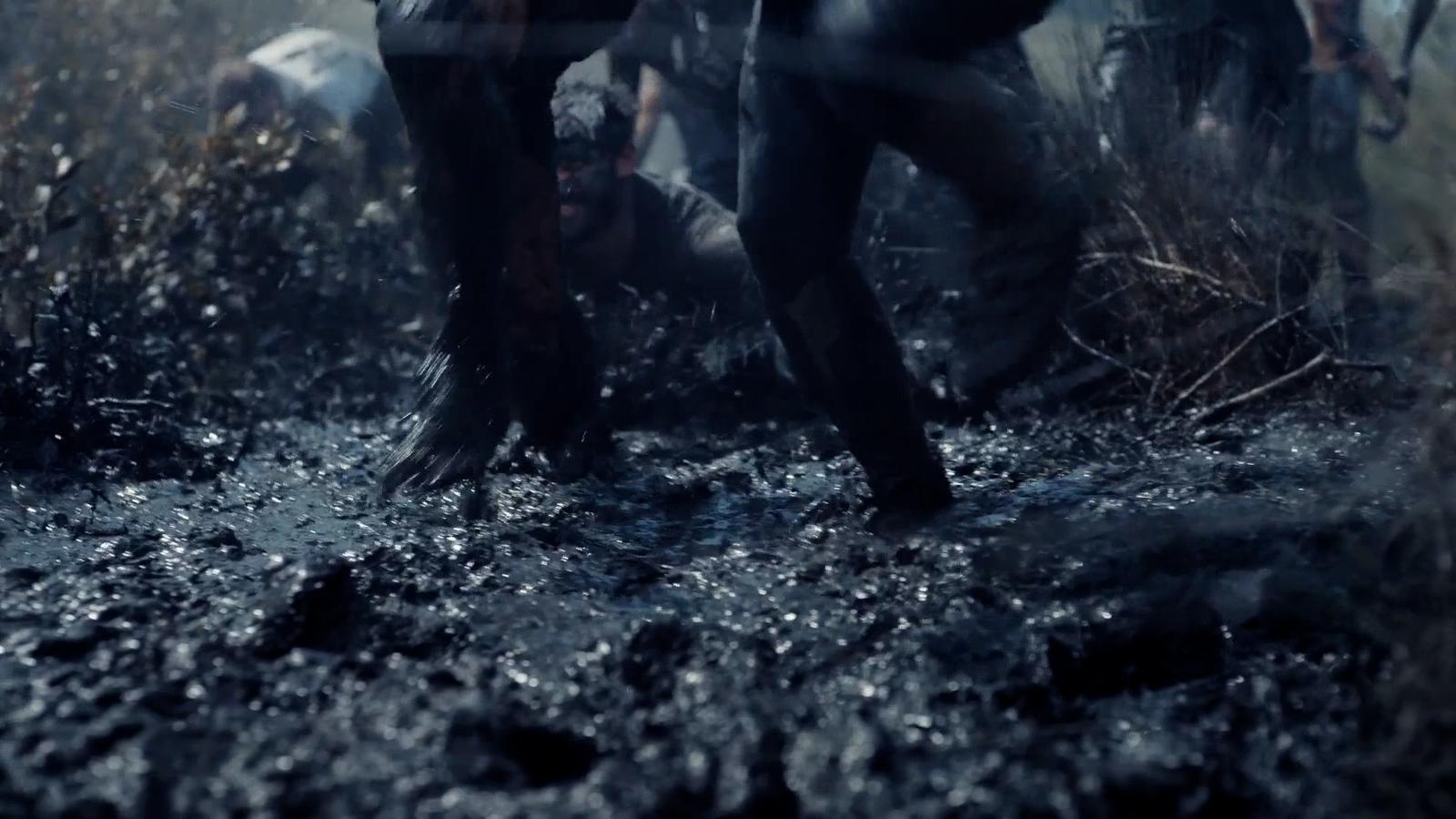 a group of people walking through a muddy field