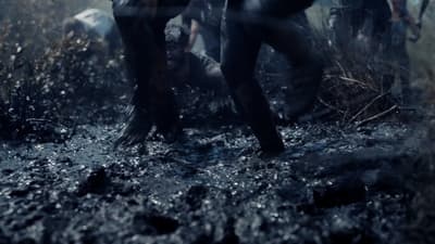 a group of people walking through a muddy field