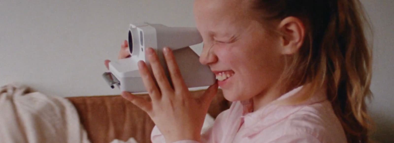a woman is smiling while holding a video camera