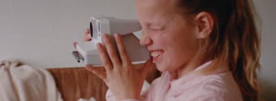 a woman is smiling while holding a video camera