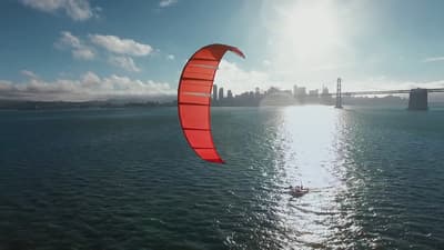 a person para sailing in the ocean with a city in the background