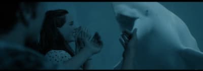 a woman standing next to a white shark in a blue room