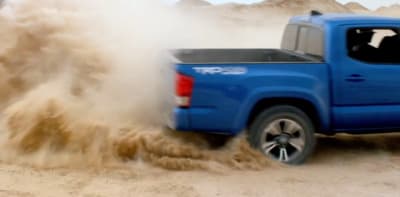 a blue pick up truck driving through sand