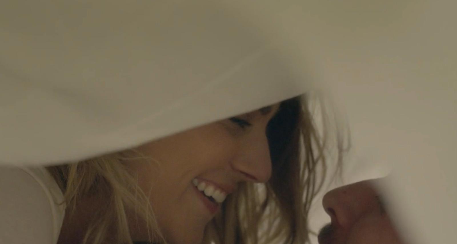 a close up of a smiling woman peeking out from behind a sheet