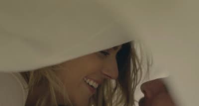 a close up of a smiling woman peeking out from behind a sheet