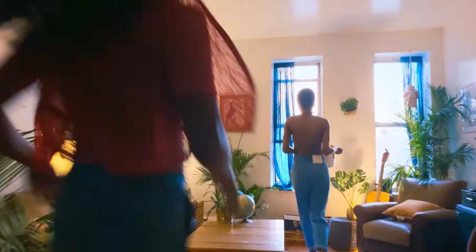 a woman standing in a living room next to a couch