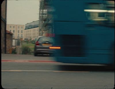 a blue bus driving down a street next to tall buildings